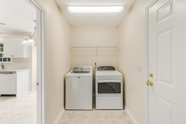 washroom featuring washing machine and dryer, a textured ceiling, and light tile patterned floors