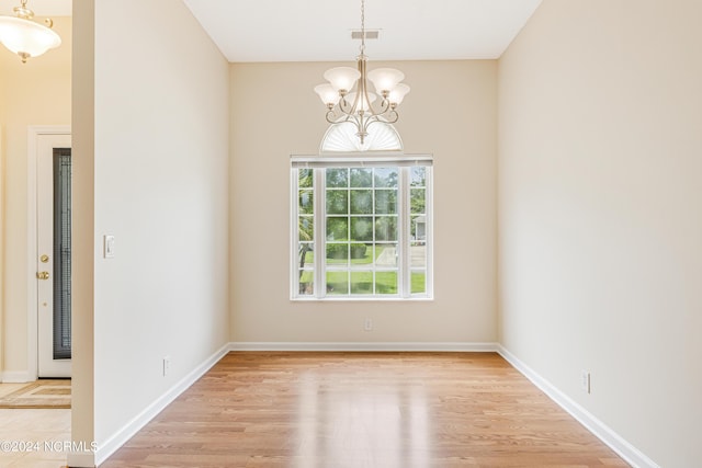 spare room featuring a chandelier and light hardwood / wood-style floors