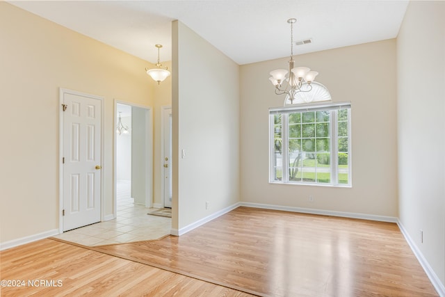 unfurnished room with a chandelier and light hardwood / wood-style floors