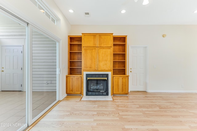 unfurnished living room with a tiled fireplace and light hardwood / wood-style flooring