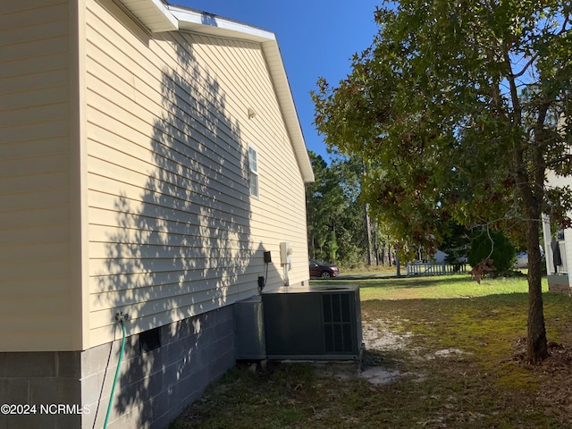 view of property exterior with a yard and central air condition unit