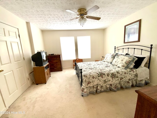 carpeted bedroom featuring ceiling fan and a textured ceiling