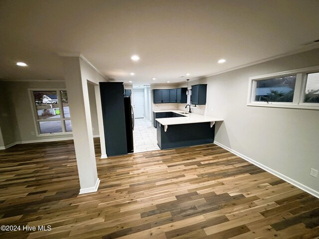 kitchen featuring pendant lighting, backsplash, sink, ornamental molding, and kitchen peninsula