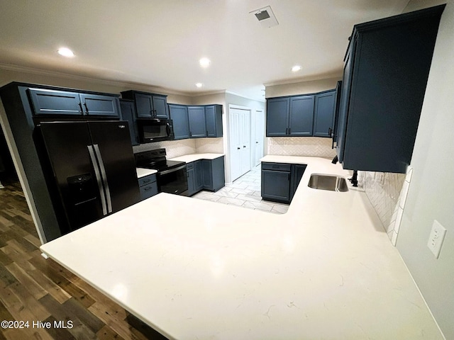 kitchen featuring tasteful backsplash, light hardwood / wood-style floors, black appliances, crown molding, and blue cabinetry