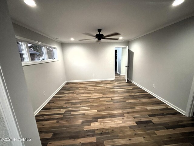 empty room featuring ceiling fan, crown molding, and dark wood-type flooring