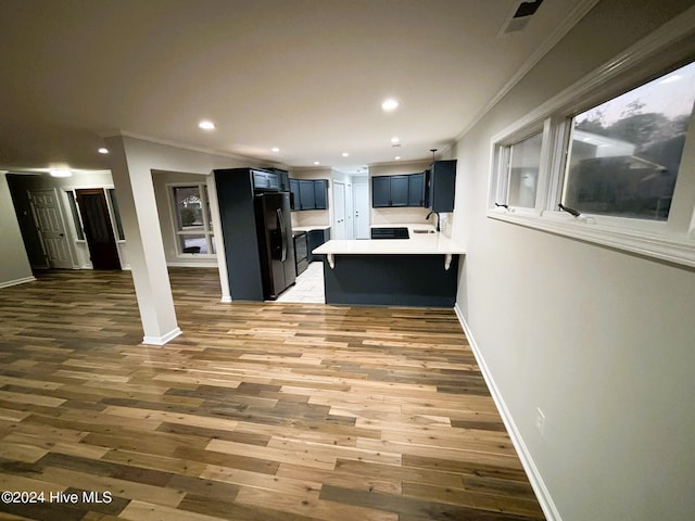 kitchen featuring blue cabinets, wood-type flooring, sink, a kitchen bar, and kitchen peninsula