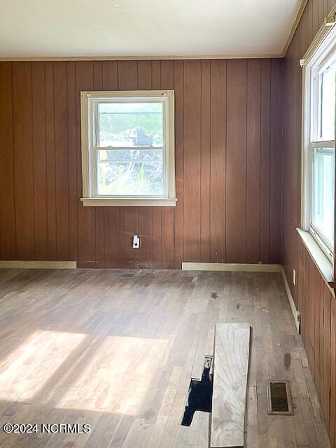 empty room featuring hardwood / wood-style flooring, plenty of natural light, and wooden walls