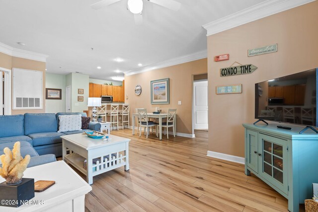 living room with light wood-type flooring, ceiling fan, and ornamental molding