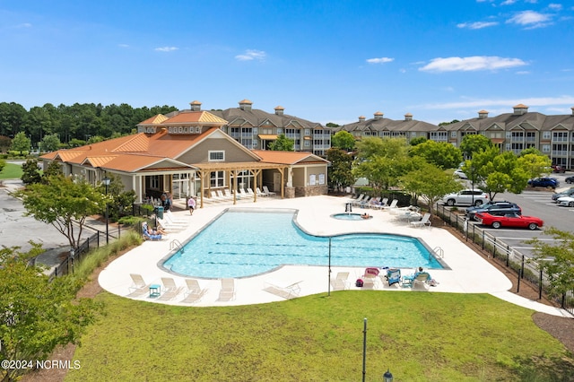 view of pool with a patio and a lawn