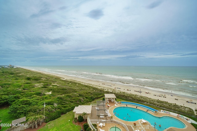 view of swimming pool featuring a view of the beach and a water view