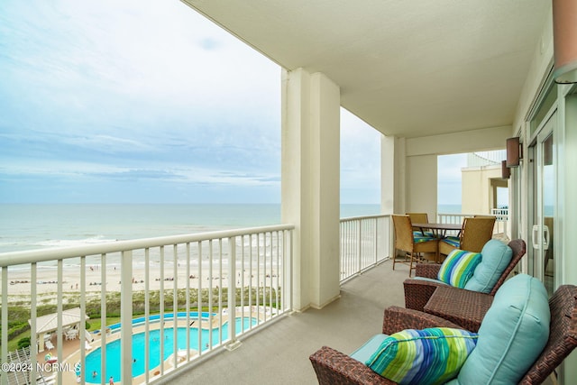 balcony featuring a view of the beach and a water view