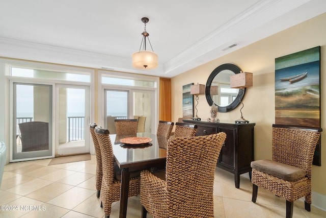 tiled dining area with a tray ceiling and crown molding