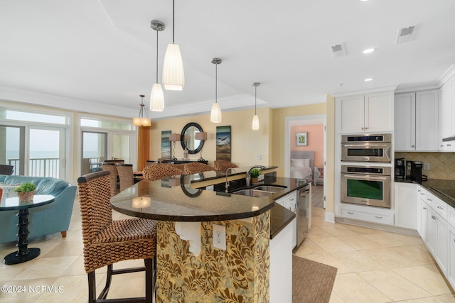 kitchen with white cabinetry, stainless steel appliances, sink, and hanging light fixtures