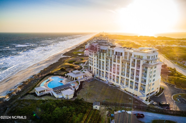 aerial view at dusk with a water view and a view of the beach