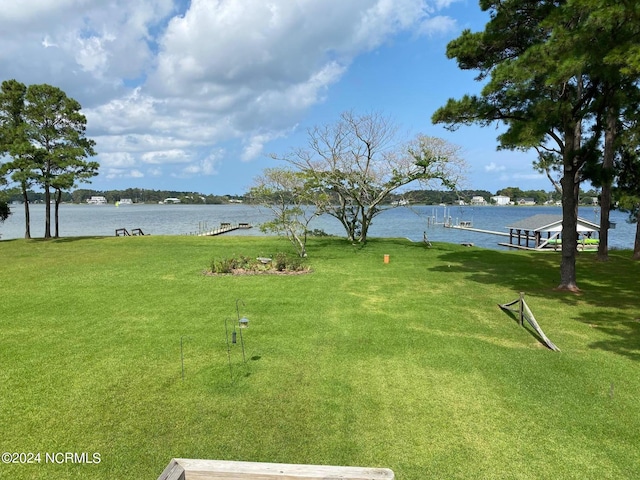 surrounding community with a dock, a yard, and a water view