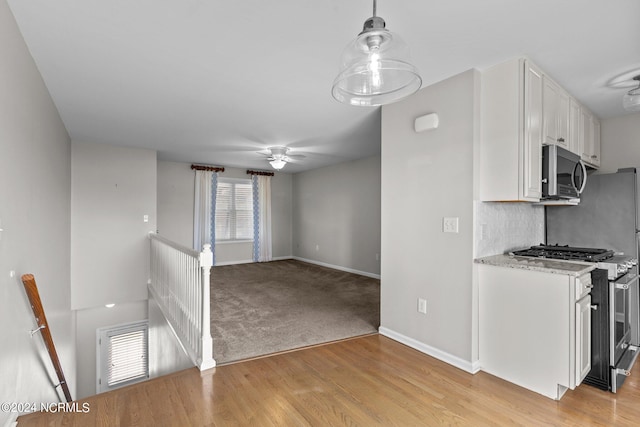 kitchen with pendant lighting, light wood-type flooring, white cabinets, appliances with stainless steel finishes, and ceiling fan