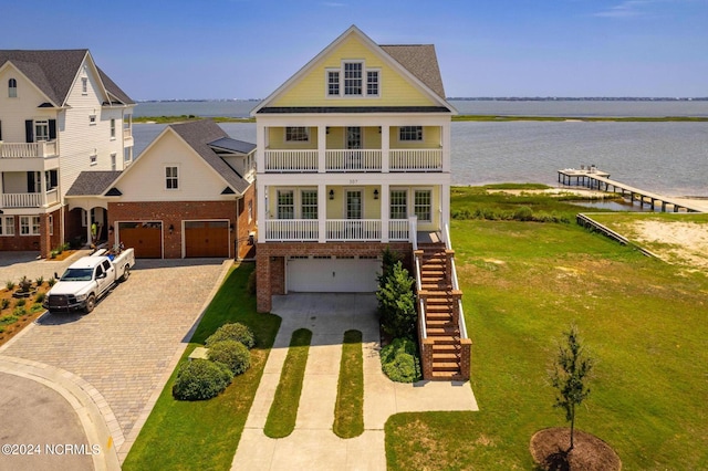 view of front of property featuring a balcony, a garage, a front yard, and a water view