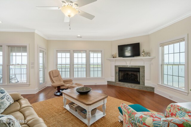 living room with ceiling fan, crown molding, dark hardwood / wood-style flooring, and a high end fireplace