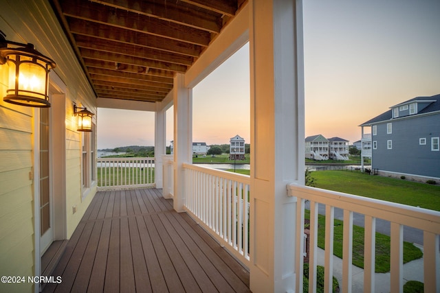 deck at dusk featuring a water view