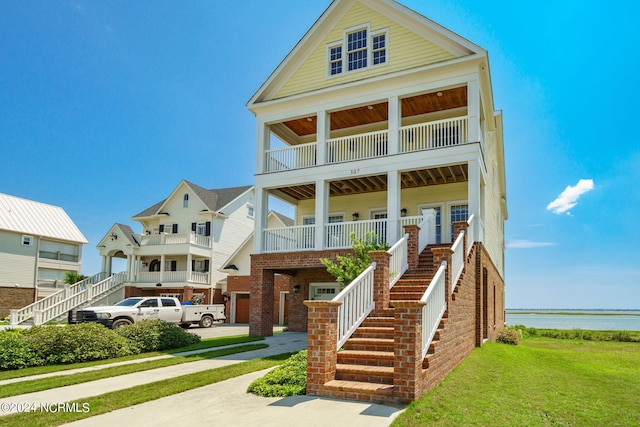 neoclassical / greek revival house featuring a porch, a balcony, and a water view