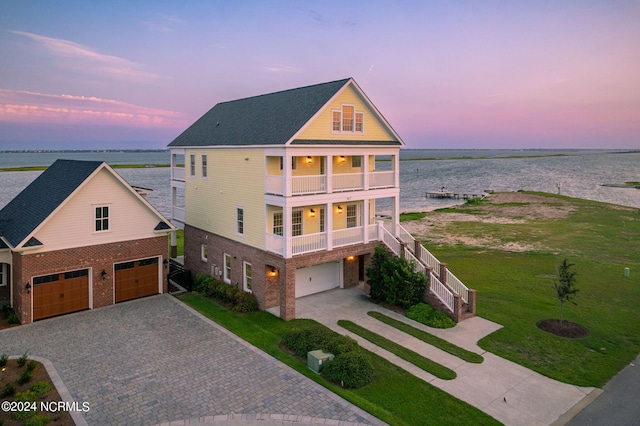 view of front facade with a water view, a balcony, a garage, and a porch