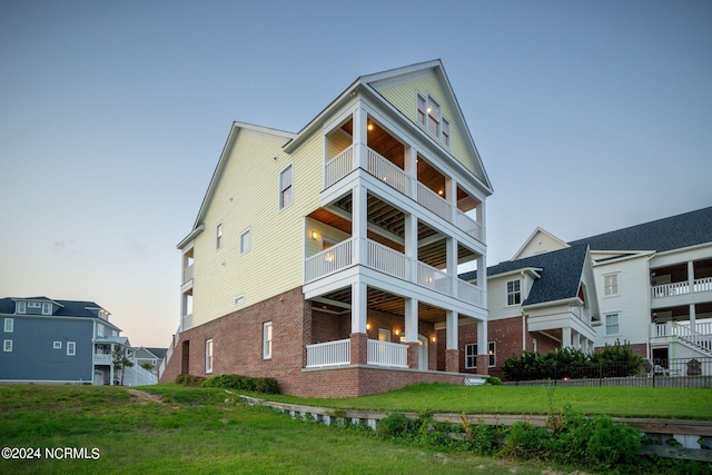 back house at dusk featuring a lawn