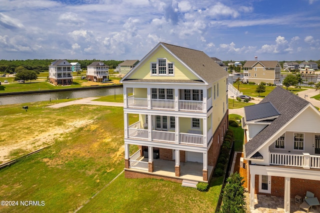 back of property featuring a water view, a balcony, and a patio area