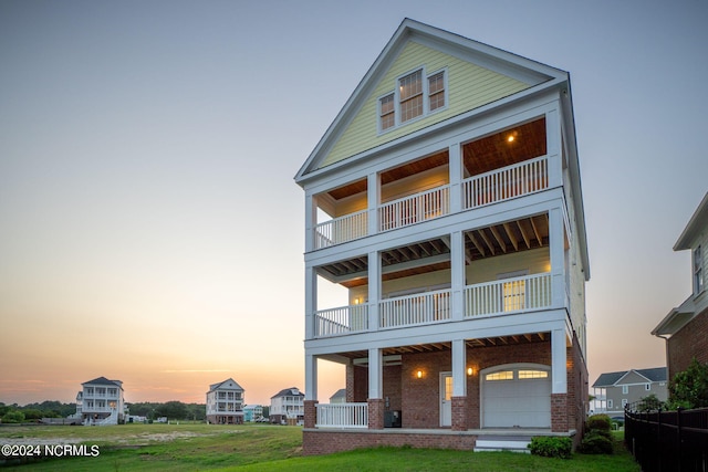 back house at dusk with a yard and a balcony