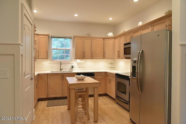 kitchen featuring stainless steel appliances, light brown cabinetry, sink, and light hardwood / wood-style flooring