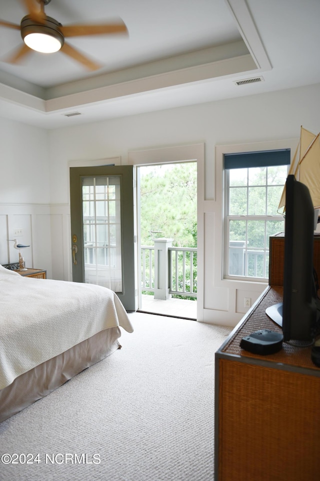 bedroom featuring a tray ceiling, access to outside, ceiling fan, and carpet flooring