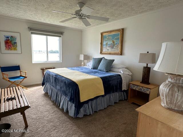 carpeted bedroom featuring ceiling fan and a textured ceiling