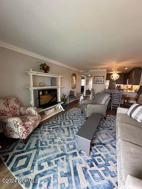 living room featuring wood-type flooring, ornamental molding, and a chandelier