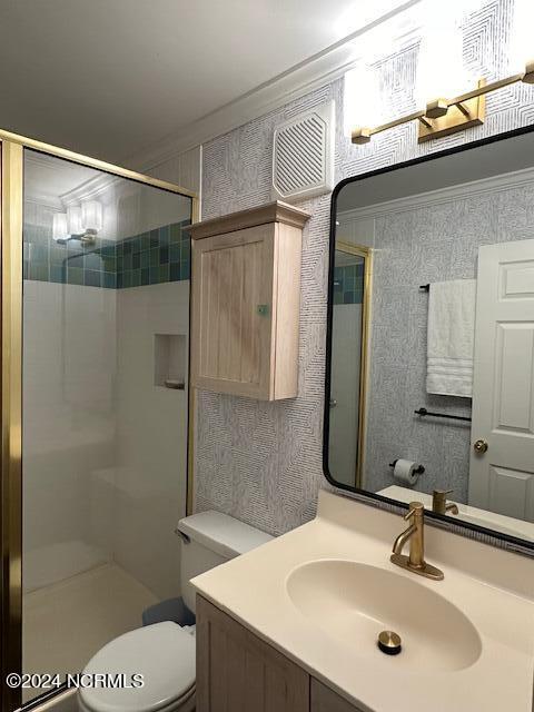 bathroom with an enclosed shower, toilet, ornamental molding, and vanity