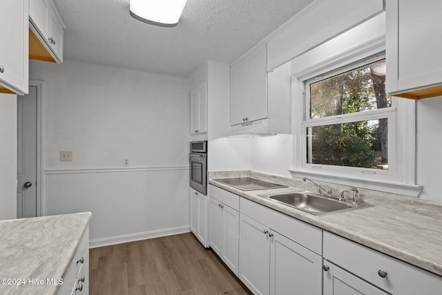 kitchen with black electric cooktop, sink, white cabinets, hardwood / wood-style floors, and oven