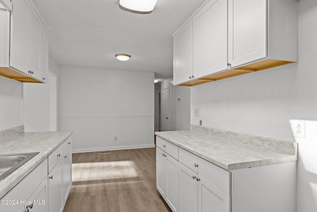 kitchen with sink, white cabinets, and light wood-type flooring