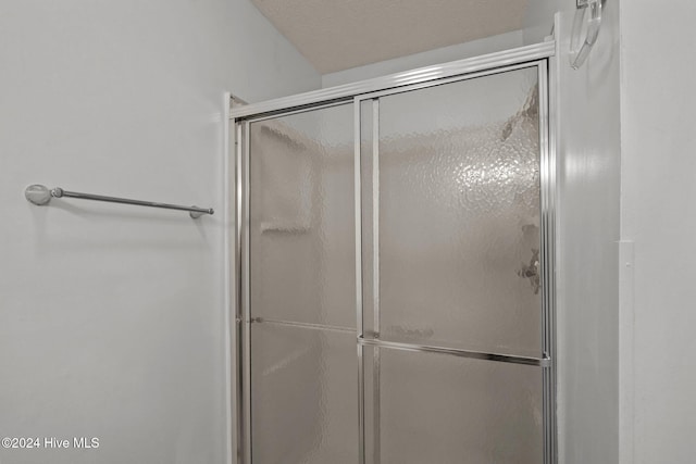 bathroom featuring a shower with shower door and a textured ceiling