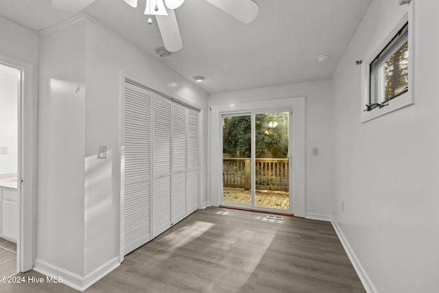 unfurnished bedroom with ceiling fan, access to exterior, light wood-type flooring, and a closet