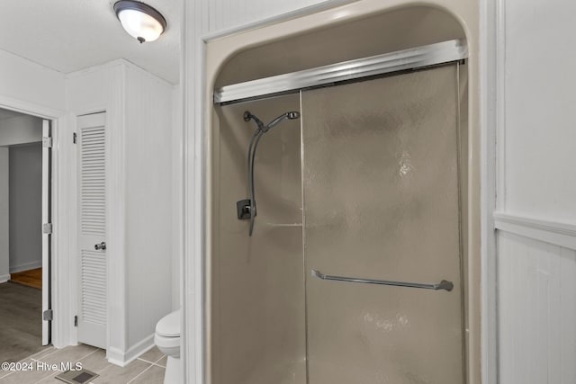 bathroom with tile patterned floors, toilet, and walk in shower