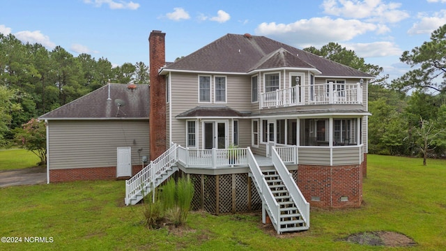 back of property with a sunroom, a deck, and a lawn