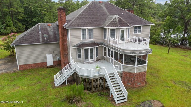 rear view of house featuring a wooden deck and a lawn