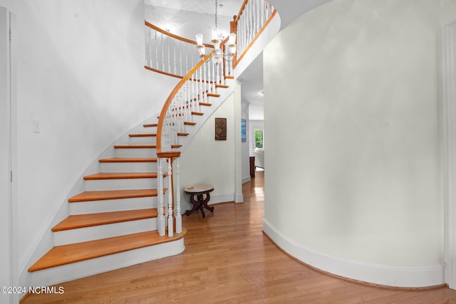 stairs with an inviting chandelier and light hardwood / wood-style flooring