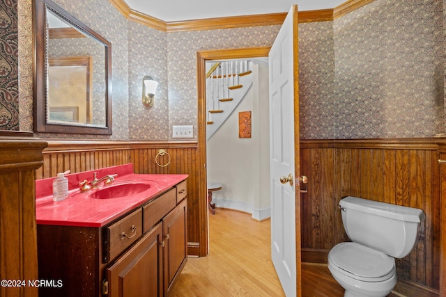 bathroom with hardwood / wood-style flooring, toilet, vanity, and ornamental molding