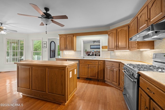 kitchen with gas range oven, tasteful backsplash, a kitchen island, light wood-type flooring, and ceiling fan