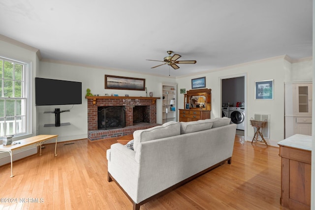 living room featuring a fireplace, ceiling fan, light wood-type flooring, ornamental molding, and washing machine and clothes dryer