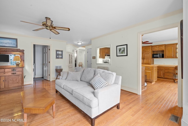 living room featuring crown molding, light hardwood / wood-style flooring, and ceiling fan