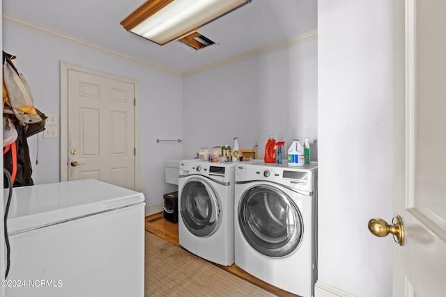 clothes washing area with separate washer and dryer and ornamental molding