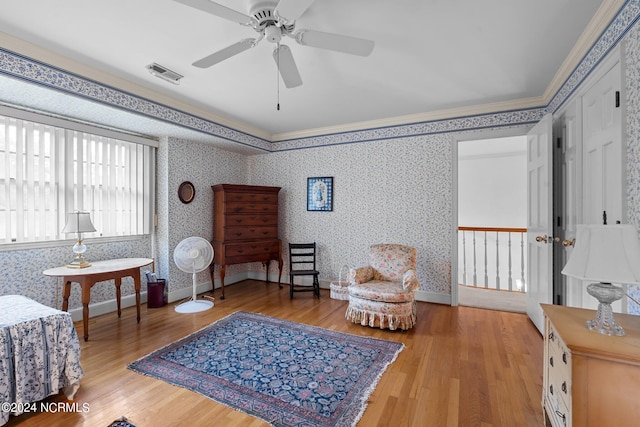 living area with light hardwood / wood-style flooring, ceiling fan, and crown molding