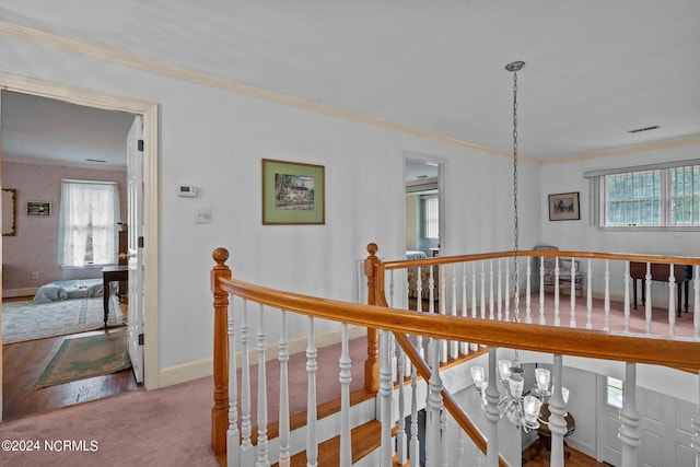 hall featuring an inviting chandelier, carpet flooring, and crown molding