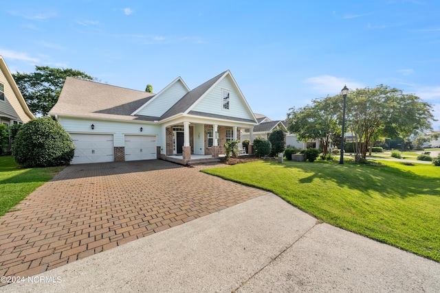 view of front of home with a garage, a front yard, and covered porch