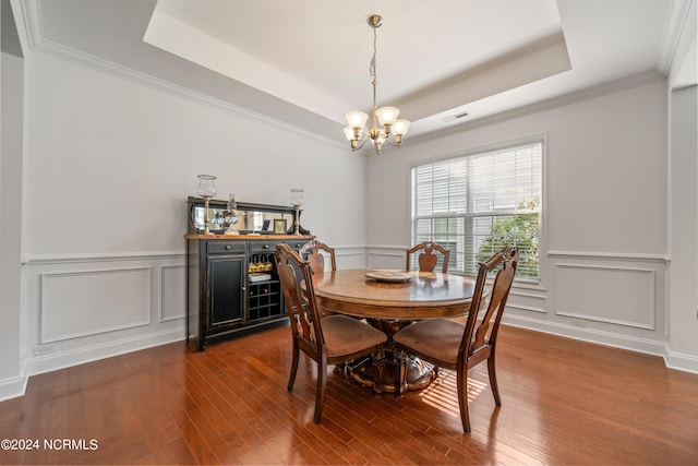 dining room with a chandelier, dark hardwood / wood-style floors, a raised ceiling, and crown molding